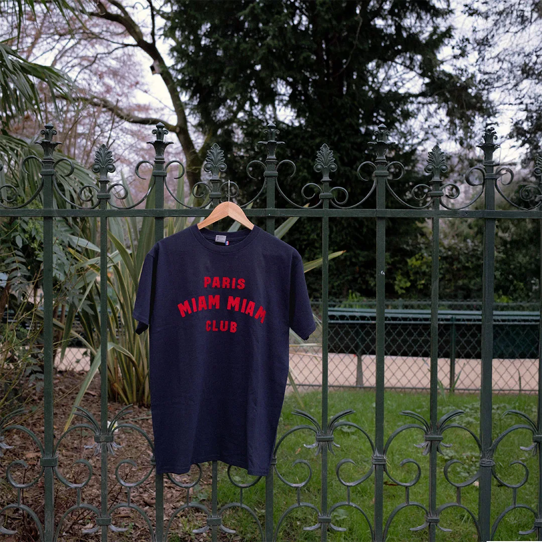 Camiseta azul marino del Paris Miam Miam Club colgada en una rejilla de jardín
