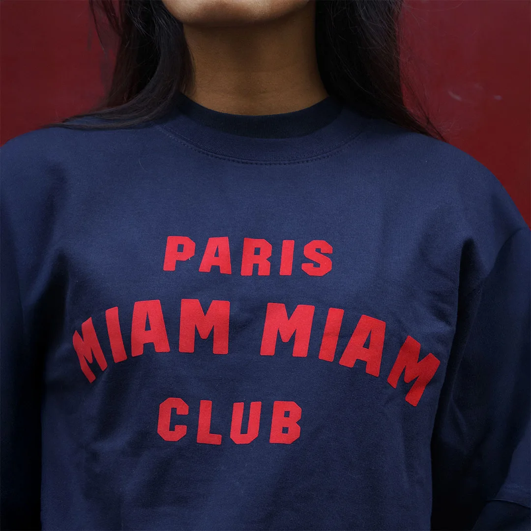 Close-up of the red Paris Miam Miam Club logo on a navy blue sweatshirt
